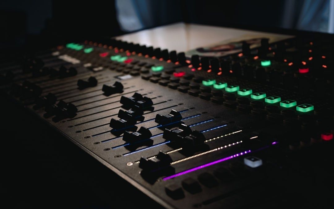 Nahaufnahme eines beleuchteten Audiomischpults mit vielen Fadern und Reglern